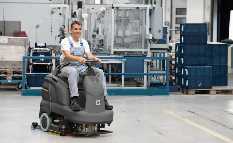 Người đàn ông lái máy chà sàn nhà xưởng